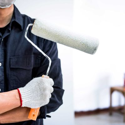 Male Painter with arm crossed holding paint roller, Interior working with paint roller in room, shape and structure.