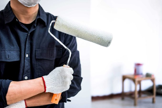 Male Painter with arm crossed holding paint roller, Interior working with paint roller in room, shape and structure.